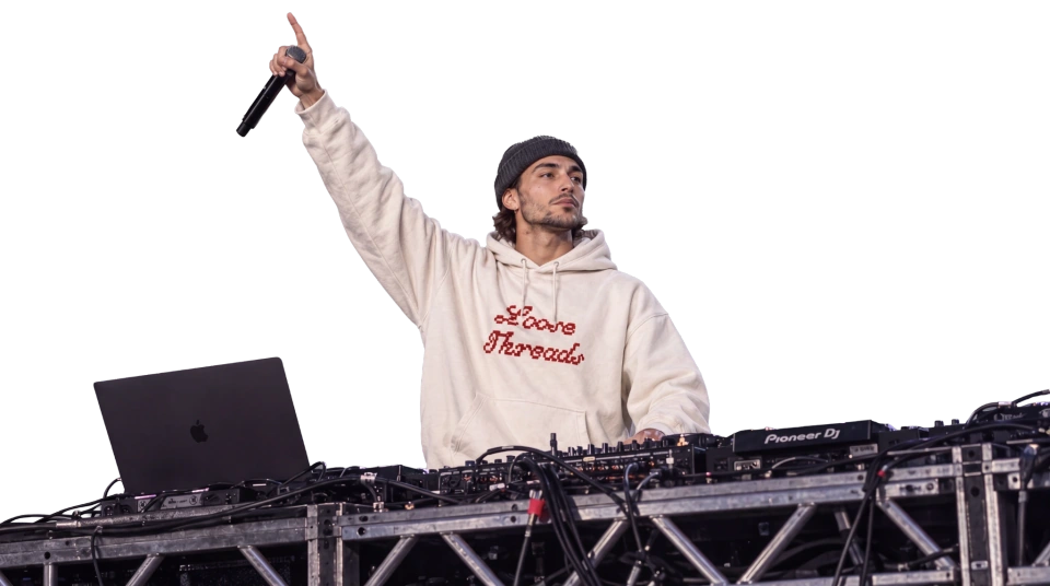 DJ Phoenix performs in the cream Loose Threads hoodie beneath red stage lights